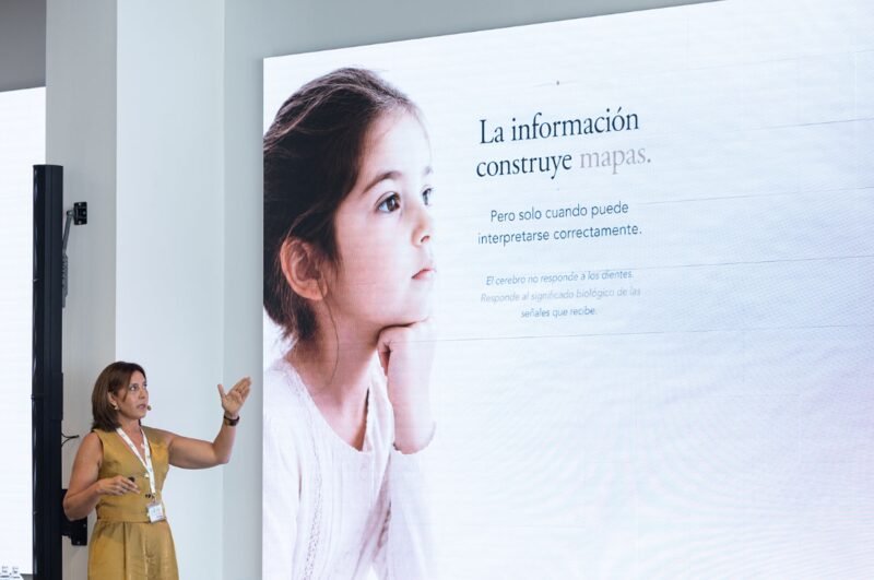 Dra. Mari Carmen Ramos durante una ponencia clínica, señalando el contenido en pantalla